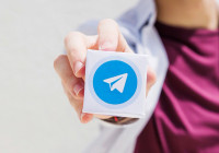 Женщина держит в руке логотип Telegram.