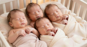 Четыре близняшки лежат в кроватке.