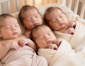 Четыре близняшки лежат в кроватке.