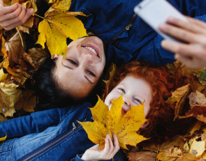 мама и сын лежат в осенних листьях