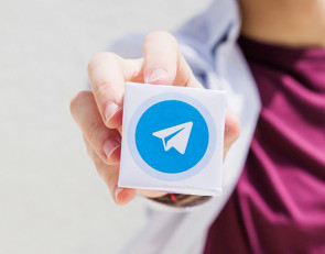 Женщина держит в руке логотип Telegram.