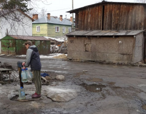 Женщина набирает воду из колонки