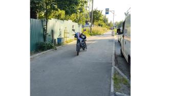 электровелосипед стоит на тротуаре у остановки общественного транспорта