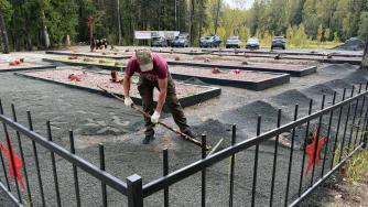 мужчина ровняет отсев на могилах бойцов