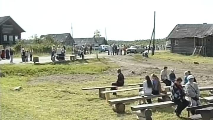 люди сидят на скамейках в деревне в Карелии