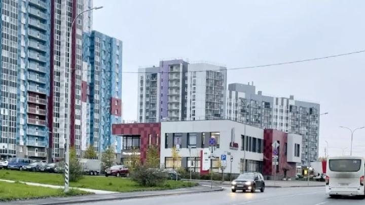 машины на проезжей части рядом с современным жилым комплексом