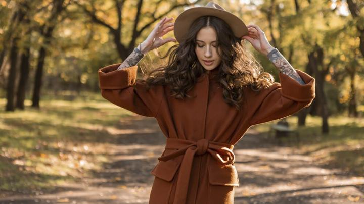 Красивая модная девушка в пальто гуляет в весеннем парке.