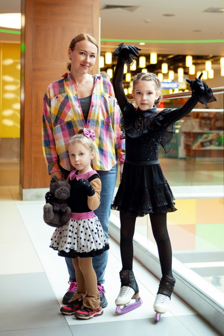 молодая женщина с двумя дочками на катке