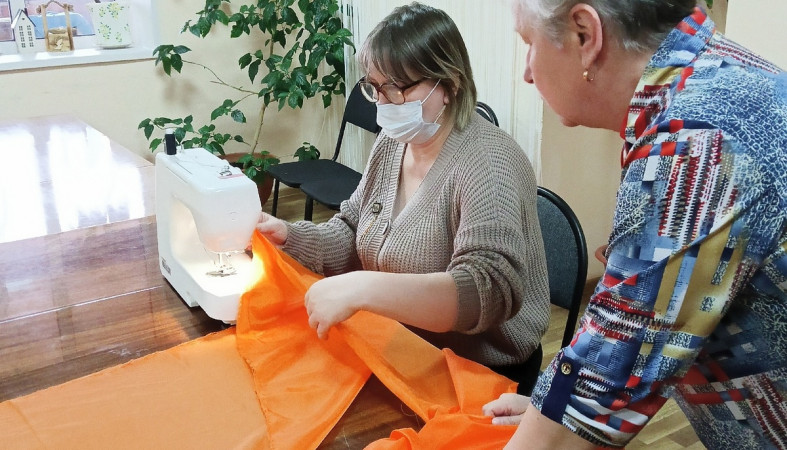 Женщина шьет Георгиевскую ленту