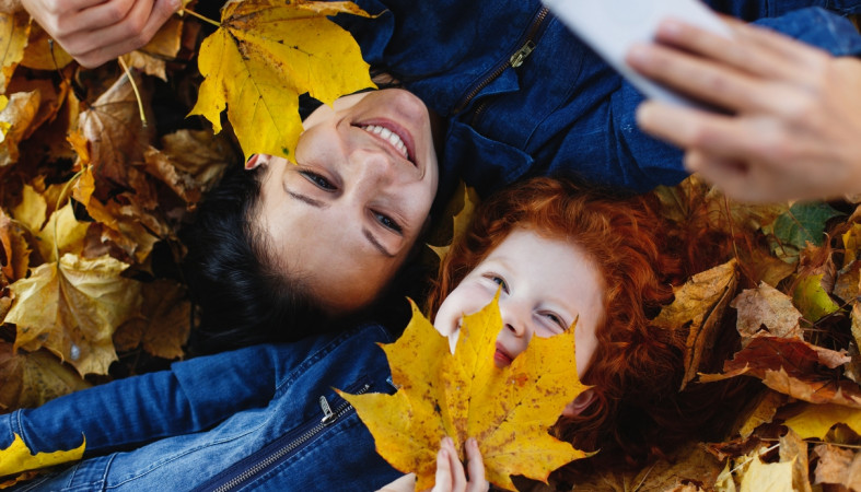 мама и сын лежат в осенних листьях мама и сын лежат в осенних листьях