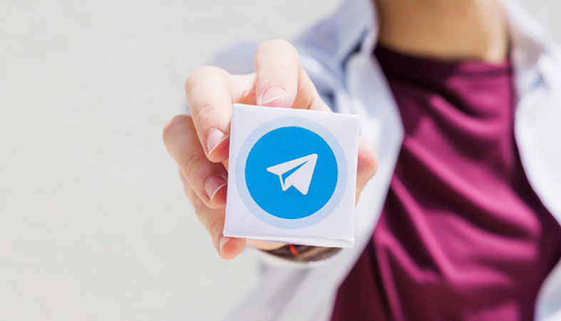 Женщина держит в руке логотип Telegram.